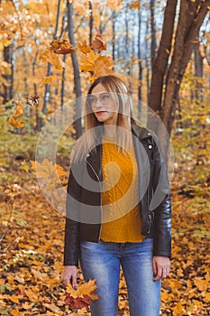 Cute smiley woman holding autumn leaves in fall park. Seasonal, lifestyle and leisure concept.