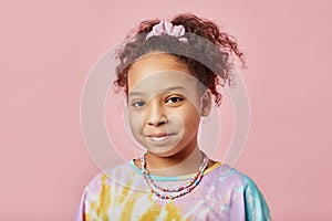 Cute smiling African American girl in t-shirt and necklace looking at camera