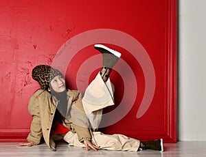 Cute asian kid girl in fashion oversize jacket and wide velvet pants lies on the floor looking at her leg she holds up