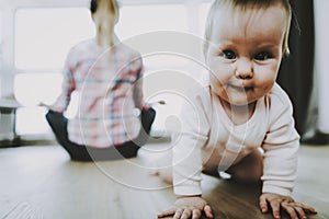 Cute Smiling Baby Crawls and Mother Sitting Back