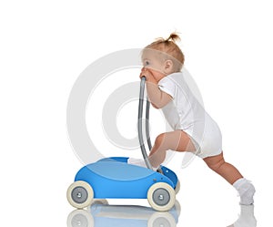 Cute smiling baby girl toddler with toy walker make first steps