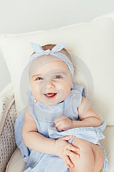 Cute smiling baby girl on white studio backgroung. 6 months baby in blue dress with big smile