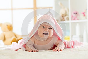 Cute baby lying on belly wrapped with pink towel after bathing