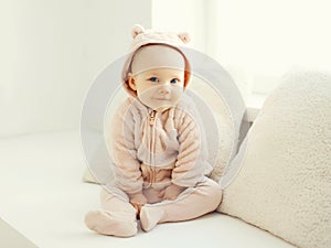 Cute smiling baby sitting in white room home