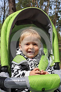 Cute smiling baby in a stroller outddor close up portrait