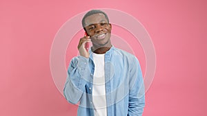 Cute smiling black man, an African American 20 years old in denim shirt, answers phone call, talks to his family on red