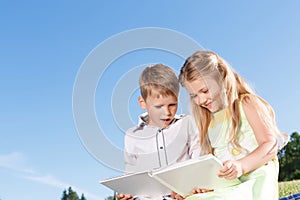 Cute smiling boy and girl reading book