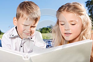 Cute smiling boy and girl reading book