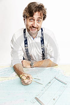 A cute smiling captain measures the distance on a map with a compass. White background.