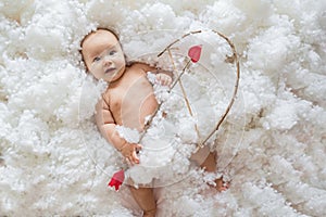 Cute smiling caucasian baby cupid on white clouds background with bow and heart arrow. Happy Valentines day concept.