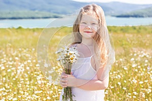 Cute smiling child girl at camomile field