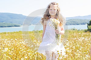 Cute smiling child girl at camomile field