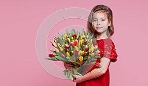 Cute smiling child girl holdi isolated on pink background. Little toddler girl gives a bouquet to mom.