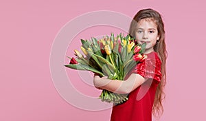 Cute smiling child girl holdi isolated on pink background. Little toddler girl gives a bouquet to mom.