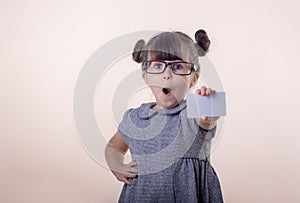 Cute smiling child with glasses holding bank card in her hands.