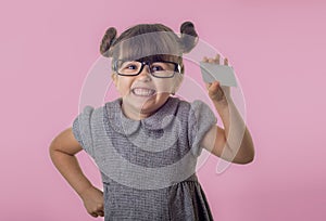 Cute smiling child with glasses holding bank card in her hands.