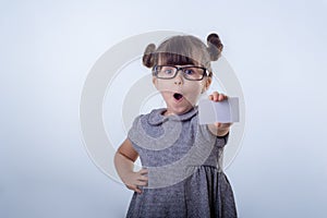 Cute smiling child with glasses holding bank card in her hands.