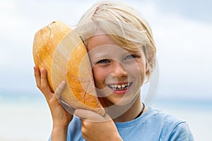 Cute, smiling child holding Baler shell to ear