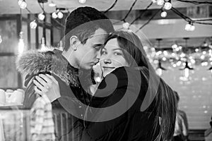 Cute smiling couple in love standing in a cafe hugging each other, image through the glass
