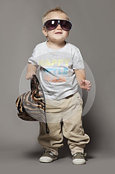 Cute smiling dancing little blond boy in suglasses