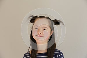 Cute smiling down syndrome girl on the grey background