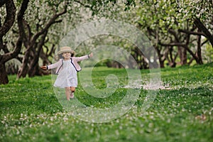 Cute smiling dressy baby girl on the walk in blooming cherry garden in spring photo