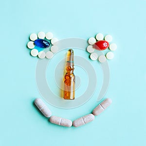 Cute smiling face made of tablets, capsules and an ampule as a nose