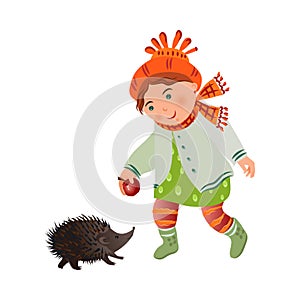 Cute smiling girl in autumn clothes give red apple to hedgehog