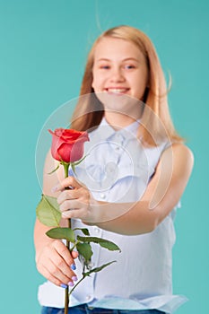 Cute smiling girl gives a red rose as a gift. Selective focus