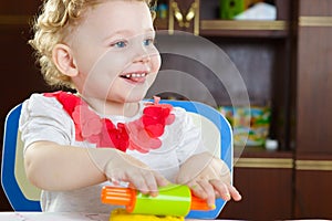 Cute smiling girl rolling plastiline dough