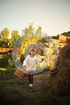 cute smiling girl runs rustic village with wicker basket  long blond hair  hayfield wheat hayloft harvesting feeding warm sunny