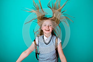 Cute smiling girl in a school dress with backpack isolated.