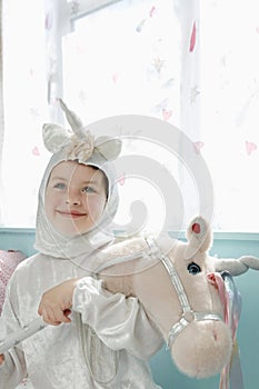 Cute Smiling Girl In Unicorn Costume With Toy Horse