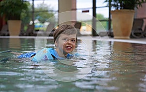 Cute smiling happy boy child swimming in a pool