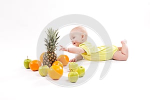 Cute smiling healthy child lies on a white background among frui