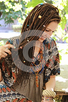 Cute smiling hippie indie style woman with dreadlocks, dressed in boho style ornamental dress posing