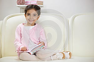 Cute smiling hispanic girl reading book