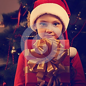 Cute smiling kid girl in Christmas santa claus hat holding the r