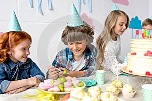 cute smiling kids eating sweets while sitting together