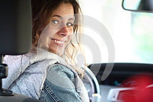 Cute smiling lady happy driving car. Portrait of happy female driver steering car looks back inside car interior