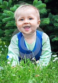 Cute smiling little baby lying on a fresh green grass in a park