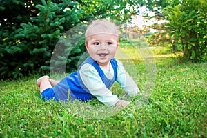 Cute smiling little baby lying on a fresh green grass in a park