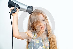 Little girl drying her long hair with hair dryer