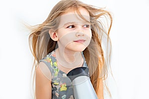 Little girl drying her long hair with hair dryer