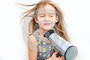 Little girl drying her long hair with hair dryer