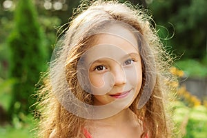 Cute smiling little girl on background of city park at summer