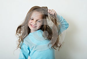 Cute smiling little girl combing her hair comb makes hair