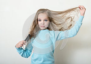 Cute smiling little girl combing her hair comb makes hair