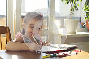 Cute smiling little girl drawing with multicolor gel pens at home, kid enjoying creative activity