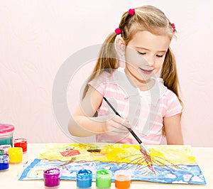 Cute smiling little girl drawing with paint and paintbrush